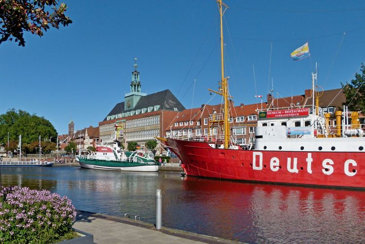 Man sieht den Ratsdelft. Im Vordergrund ein Blumenkasten, auf der gegenüberliegenden Seite das Feuerschiff und der Seenotrettungskreuzer Georg Breusing. Am Kopf des Delftes liegt das Hafenboot. Im Hintergrund ist das ostfriesische Landesmuseum zu sehen. 