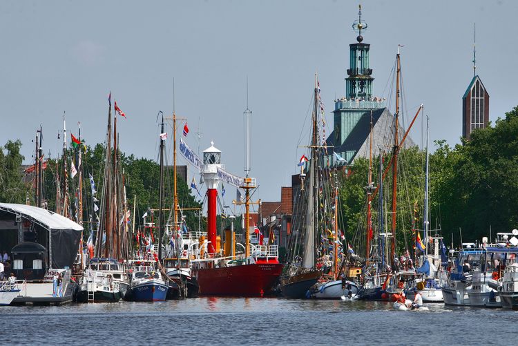 Festlich geschmückte Segelschiffe und das Feuerschiff im Delft. Eine Bühne ist aufgebaut und im Hintergrund ist das ostfriesische Landesmuseum zu sehen.