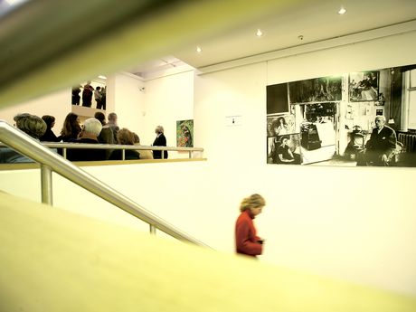 Sehr helle Aufnahme von der Kunsthalle von innen. Eine Person geht eine Treppe runter, eine Personengruppe im Hintergrund schaut sich Bilder an